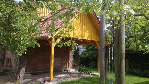 Ein Carport mit Spitzdach umgeben vpn Bäumen
