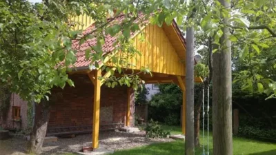 Ein Carport mit Spitzdach umgeben von Bäumen