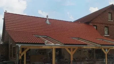 Terrassenüberdachung mit Ziegeldach und Glaselementen vor Einfamilienhaus
